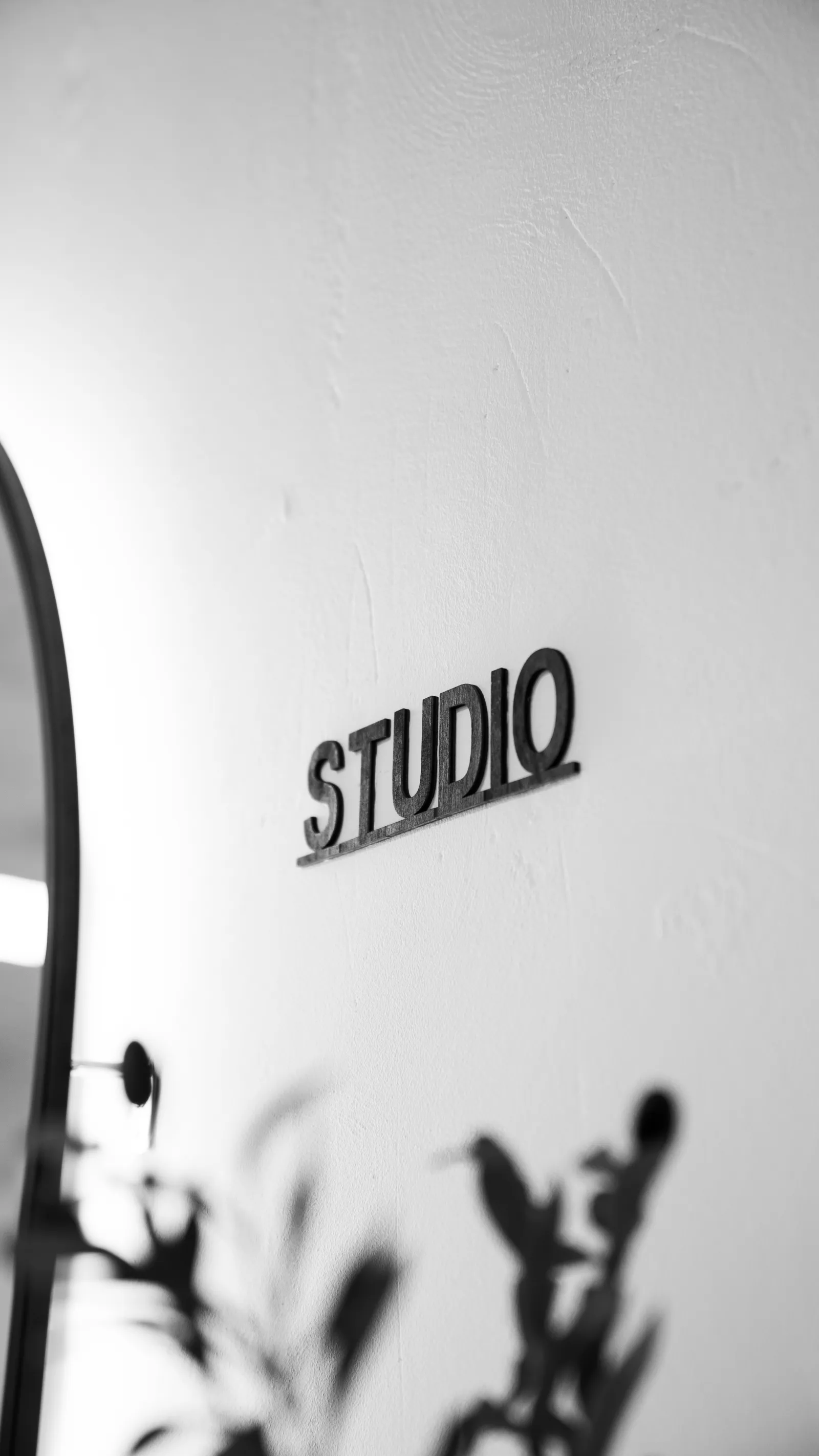 STUDIO-Schriftzug an der Wand, davor unscharfe Olivenzweige